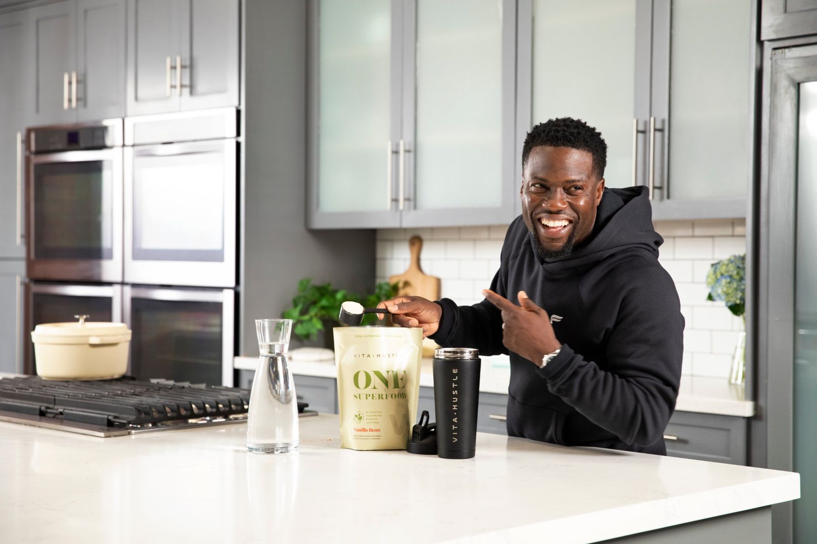 Kevin Hart scooping VitaHustle ONE in his kitchen